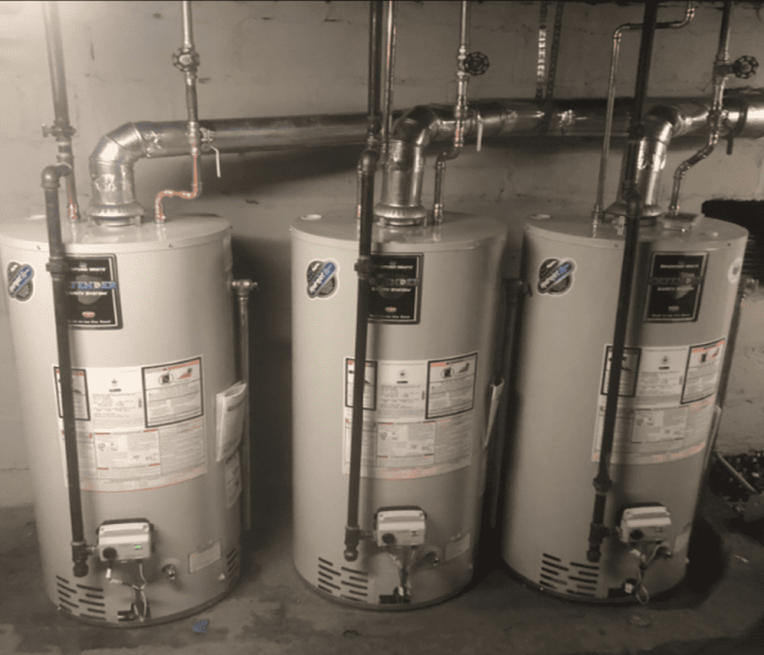 three hot water heaters in a mechanical room.